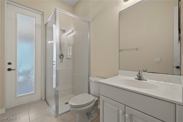 bathroom with a shower with door, vanity, tile patterned floors, and toilet