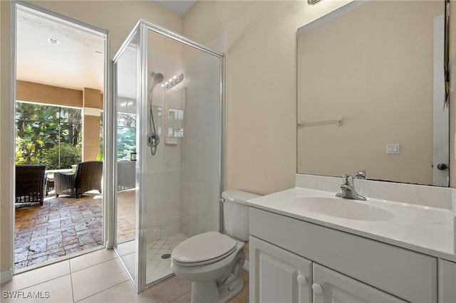 bathroom with vanity, tile patterned flooring, a shower with door, and toilet