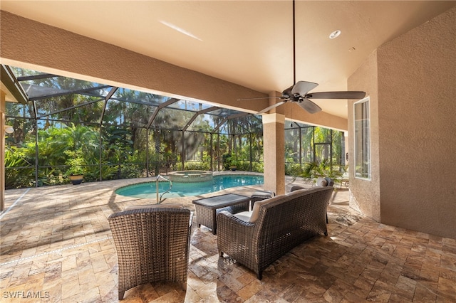 view of patio featuring ceiling fan, glass enclosure, and an in ground hot tub