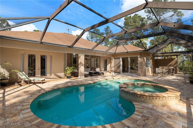 view of pool featuring a patio, glass enclosure, and an in ground hot tub