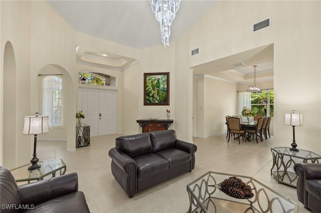 living room featuring ornamental molding, a tray ceiling, a high ceiling, and a notable chandelier