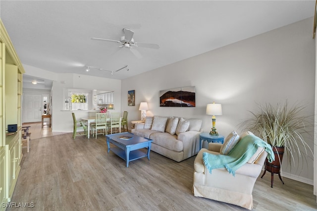 living room with ceiling fan, rail lighting, and light hardwood / wood-style floors