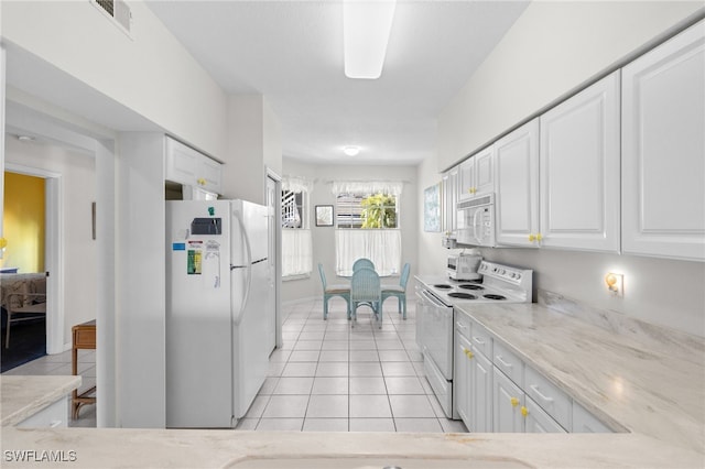 kitchen featuring light tile patterned flooring, white appliances, light stone counters, and white cabinets