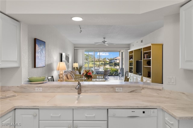 kitchen with a ceiling fan, a sink, open floor plan, white cabinetry, and white dishwasher