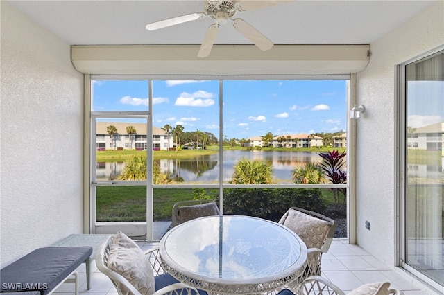 sunroom with ceiling fan and a water view