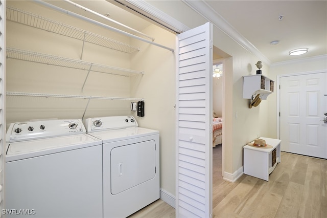 laundry area featuring crown molding, washing machine and clothes dryer, and light hardwood / wood-style flooring