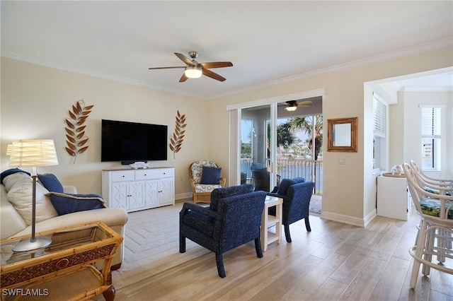 living area with light wood finished floors, a ceiling fan, baseboards, and crown molding