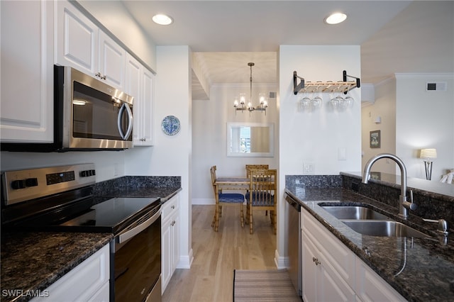 kitchen featuring sink, white cabinetry, decorative light fixtures, dark stone counters, and stainless steel appliances