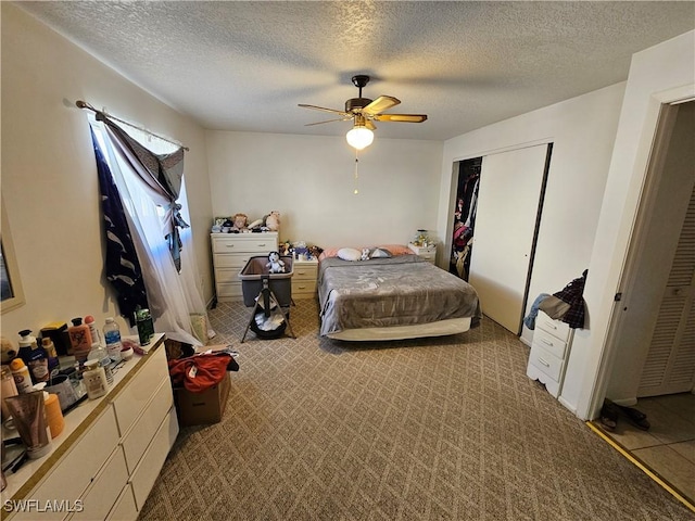 bedroom featuring a textured ceiling, light colored carpet, a closet, and ceiling fan