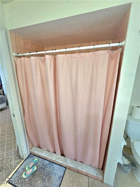 bathroom featuring tile patterned flooring, toilet, and a textured ceiling