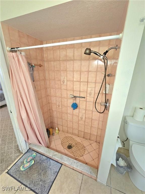 bathroom featuring toilet, a shower with shower curtain, and a textured ceiling