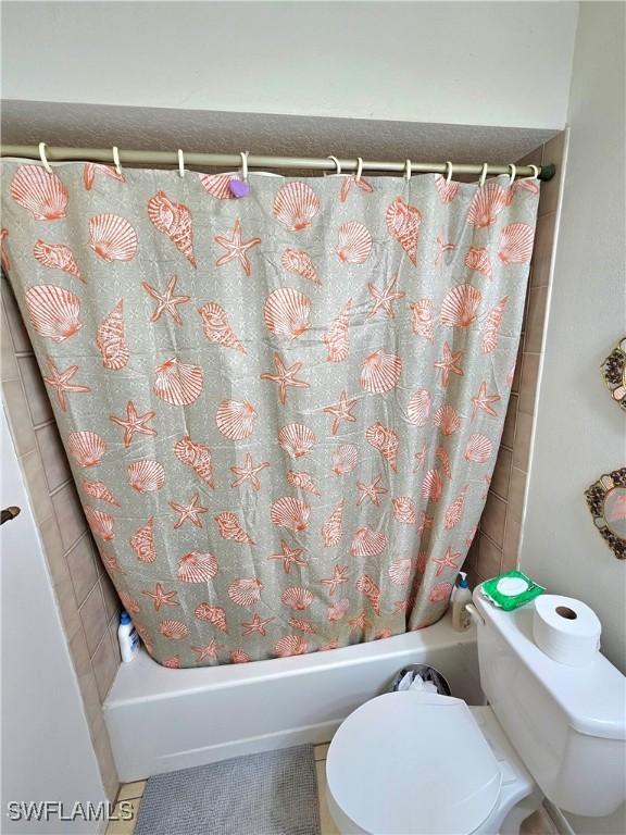 bathroom featuring tile patterned floors, shower / bath combination with curtain, and toilet