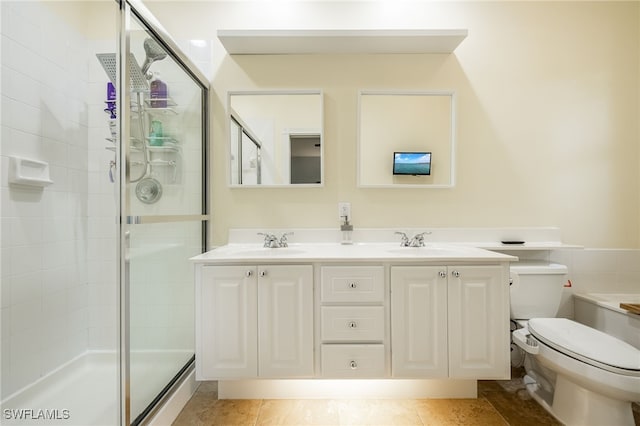 bathroom featuring tile patterned floors, vanity, toilet, and a shower with door