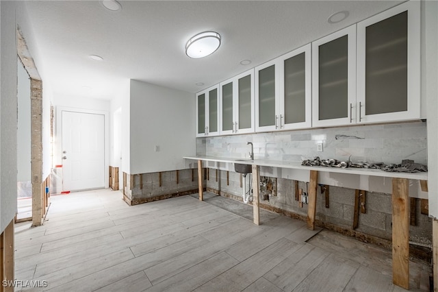 kitchen with white cabinetry, tasteful backsplash, and light hardwood / wood-style flooring