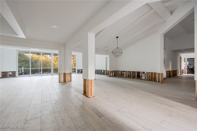 empty room with a notable chandelier, beam ceiling, high vaulted ceiling, and light wood-type flooring