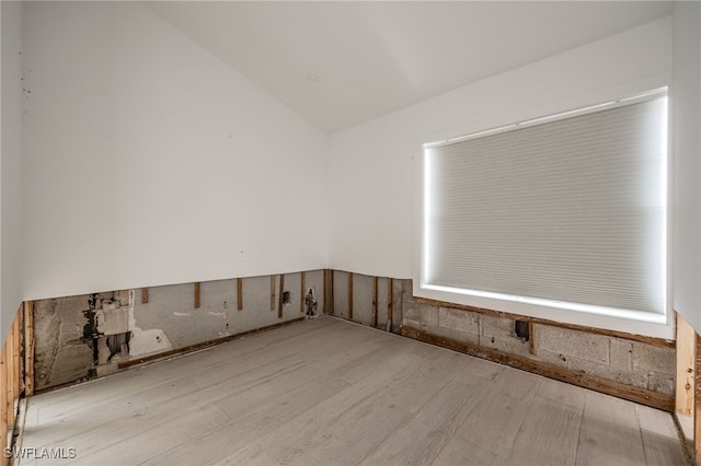 spare room featuring lofted ceiling and light hardwood / wood-style floors