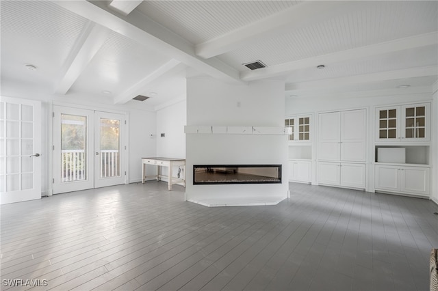 unfurnished living room with wood-type flooring, beam ceiling, and french doors