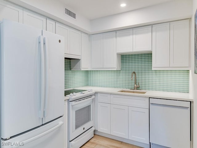 kitchen with sink, white cabinets, decorative backsplash, white appliances, and light wood-type flooring