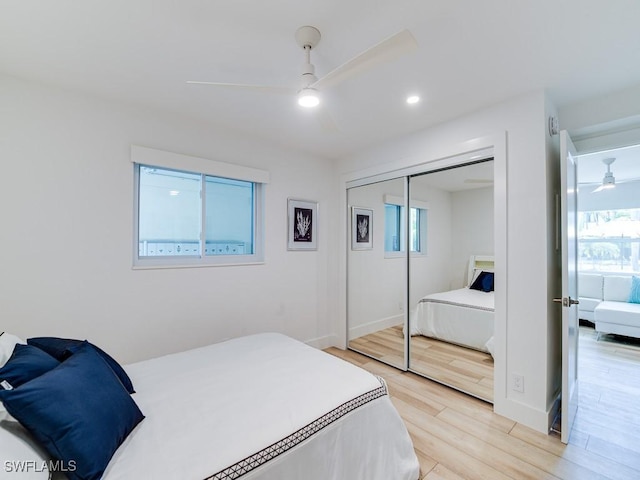 bedroom with multiple windows, light hardwood / wood-style flooring, a closet, and ceiling fan