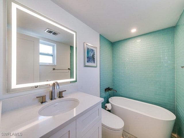 bathroom featuring vanity, toilet, and a washtub