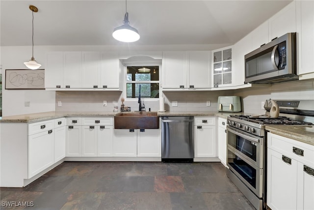 kitchen featuring tasteful backsplash, appliances with stainless steel finishes, white cabinets, and decorative light fixtures