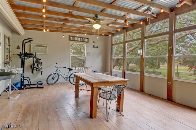 interior space with ceiling fan, a wall mounted air conditioner, beam ceiling, and light hardwood / wood-style flooring