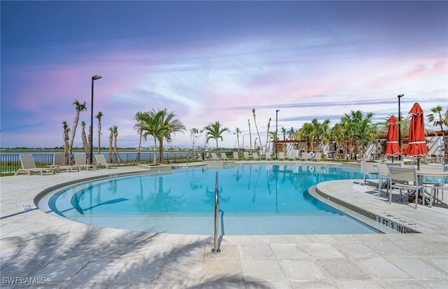 pool at dusk featuring a patio area