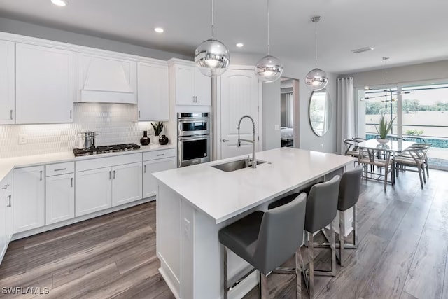 kitchen with white cabinetry, gas cooktop, sink, and custom exhaust hood