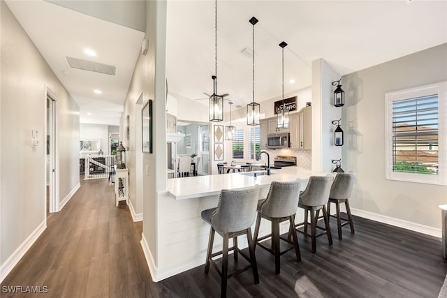 kitchen featuring pendant lighting, backsplash, stainless steel appliances, a kitchen breakfast bar, and kitchen peninsula