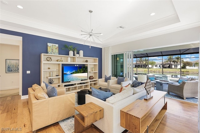 living room featuring a raised ceiling, crown molding, and light hardwood / wood-style floors