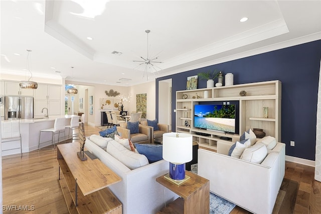 living room with an inviting chandelier, hardwood / wood-style floors, and a tray ceiling