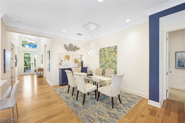 dining room featuring french doors, ornamental molding, and light wood-type flooring