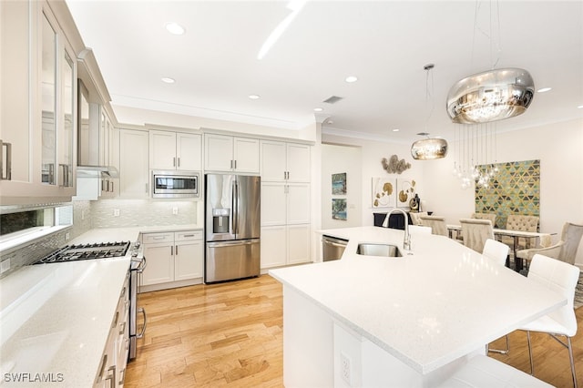 kitchen with pendant lighting, sink, a breakfast bar, stainless steel appliances, and a center island with sink