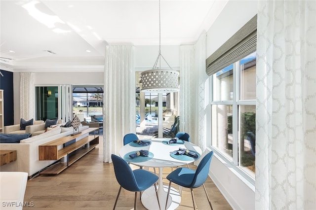 dining space with hardwood / wood-style floors, crown molding, and a wealth of natural light