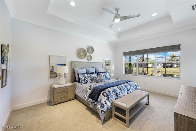 bedroom featuring a raised ceiling, light carpet, and ceiling fan