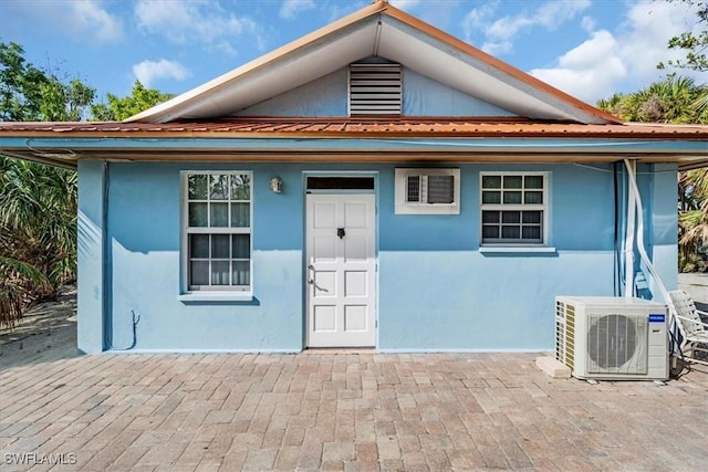 view of front facade with ac unit, metal roof, and stucco siding