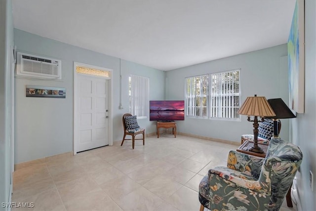 sitting room with light tile patterned floors, baseboards, and a wall mounted AC