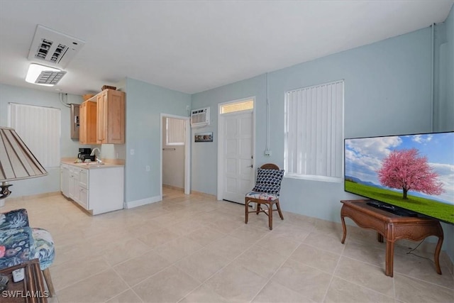 living area featuring an AC wall unit and baseboards