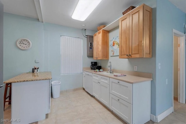 kitchen featuring light countertops, light brown cabinetry, white dishwasher, and a sink