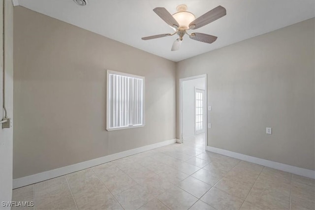 empty room featuring light tile patterned flooring, ceiling fan, and baseboards