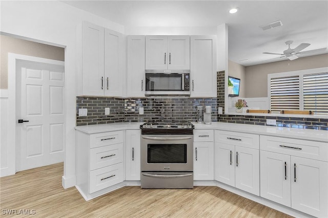 kitchen with stainless steel appliances, white cabinetry, backsplash, and light hardwood / wood-style floors