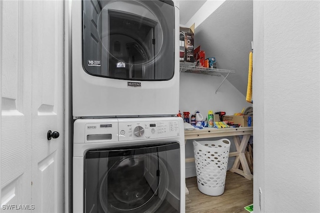 laundry room featuring hardwood / wood-style flooring and stacked washing maching and dryer