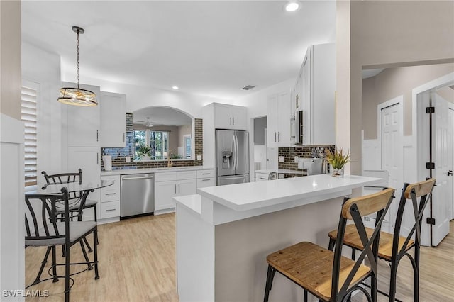 kitchen featuring a breakfast bar area, white cabinetry, hanging light fixtures, appliances with stainless steel finishes, and kitchen peninsula