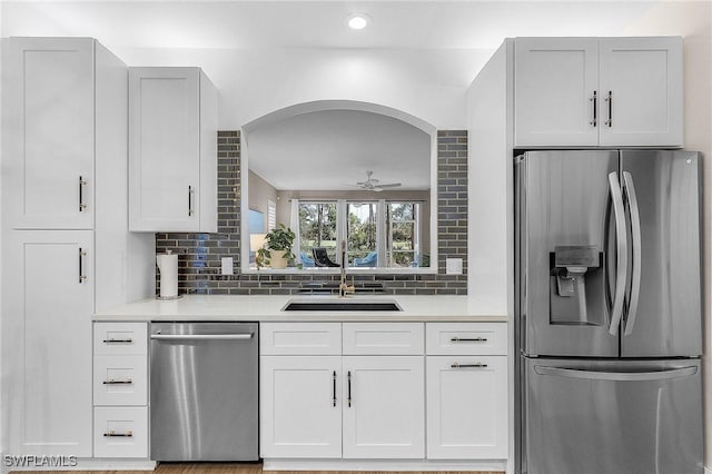 kitchen with sink, ceiling fan, stainless steel appliances, white cabinets, and decorative backsplash