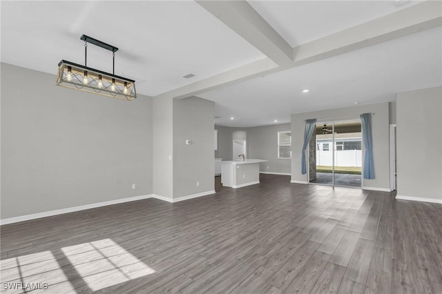 unfurnished living room with dark hardwood / wood-style floors, sink, and beam ceiling