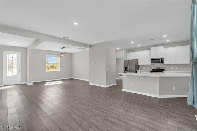 kitchen with sink, white cabinetry, hanging light fixtures, hardwood / wood-style flooring, and stainless steel appliances