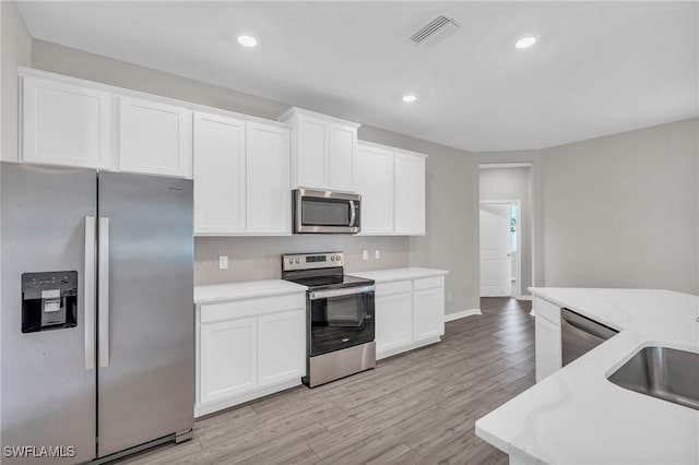 kitchen featuring stainless steel appliances, sink, light hardwood / wood-style flooring, and white cabinets