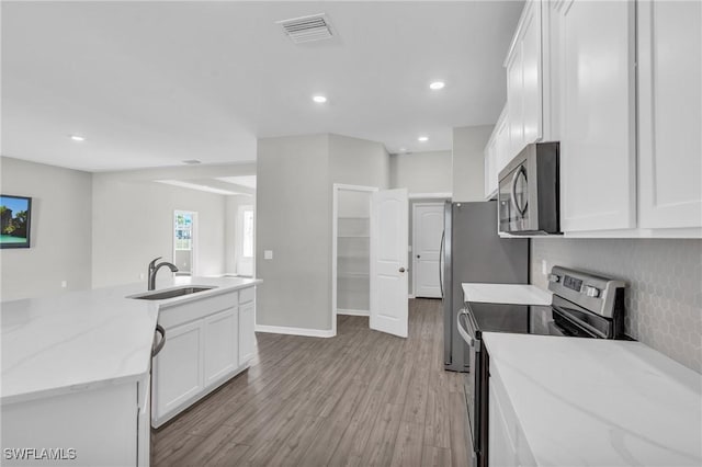 kitchen featuring sink, appliances with stainless steel finishes, light stone countertops, white cabinets, and light wood-type flooring