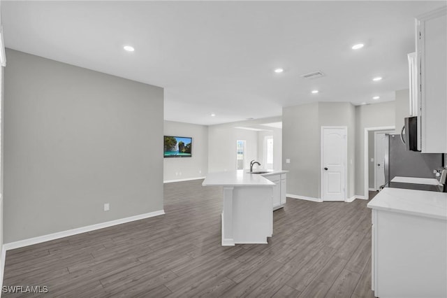 kitchen with sink, white cabinetry, stove, a center island with sink, and dark hardwood / wood-style flooring