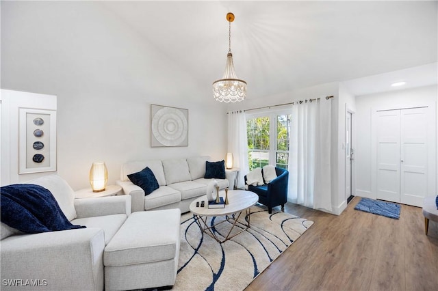 living room with an inviting chandelier, light hardwood / wood-style flooring, and high vaulted ceiling